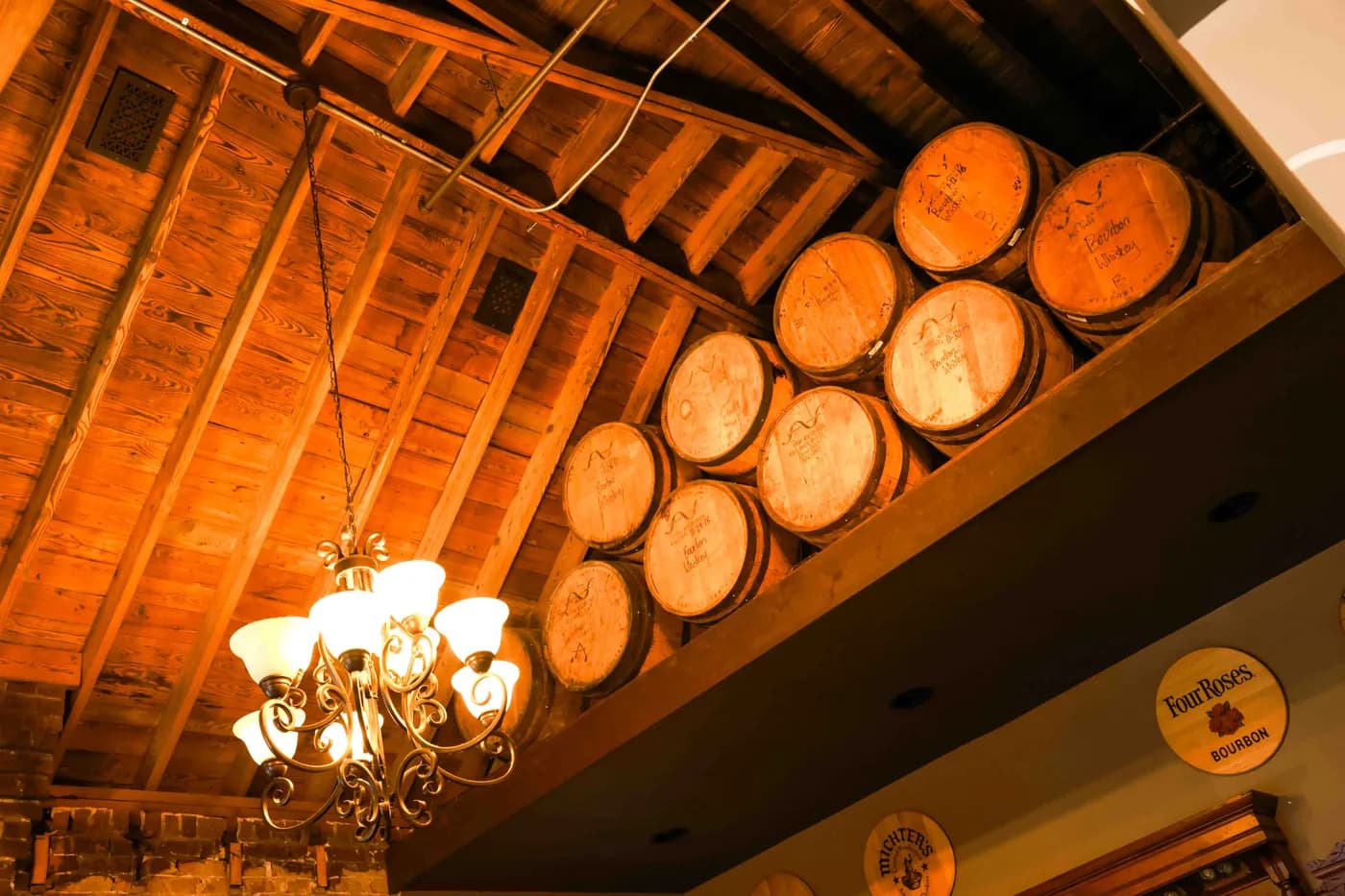 Bourbon barrels stacked in the rafters above The Boardroom, beside a chandelier