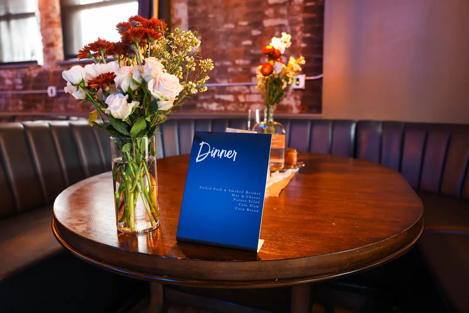 A buffet menu card on a booth table beside a vase of flowers