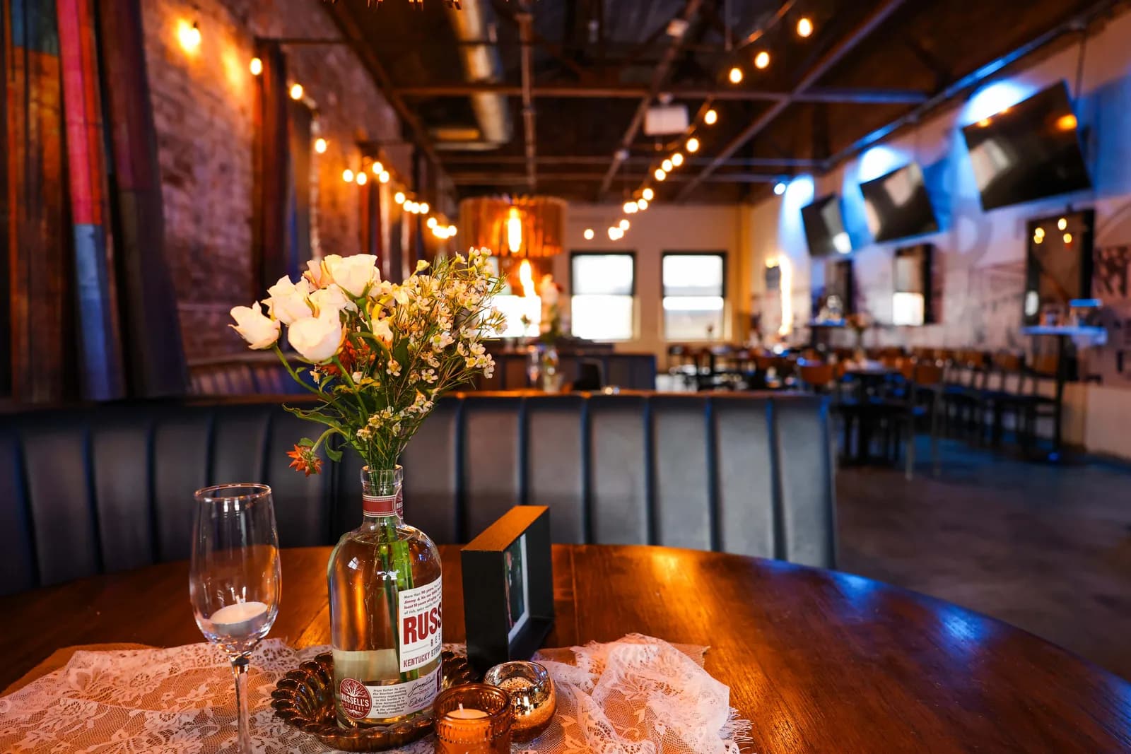 A table laid with flowers and candles, the bar and screens behind